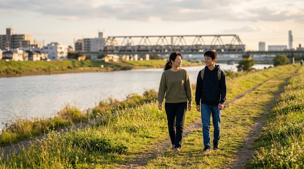 夕方の河川敷の道を、話しながら並んで歩く母親と高校生の息子