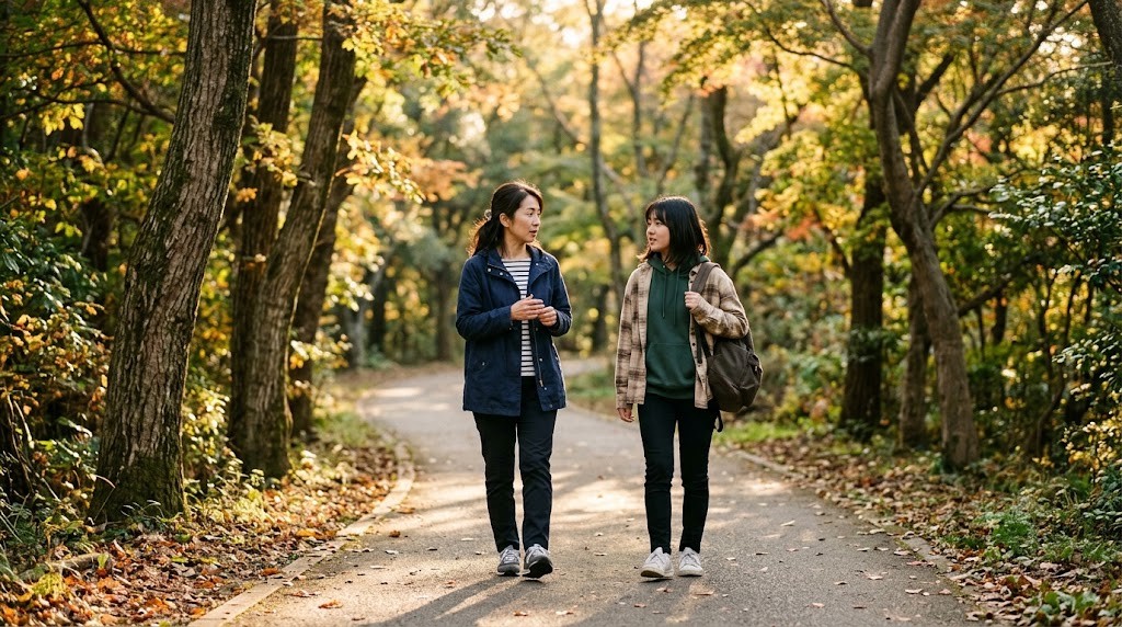 紅葉した公園の道を並んで歩く保護者と高校生